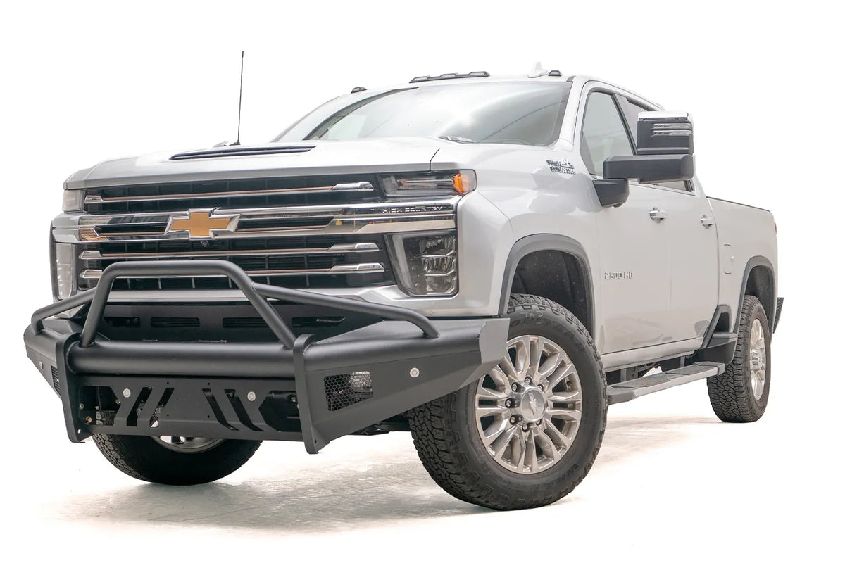 Fab Fours Black Steel Elite front bumper with pre-runner guard on a silver Chevrolet Silverado 2500HD, front driver-side three-quarter view, showing the pre-runner guard, slotted skid plate and mesh light openings