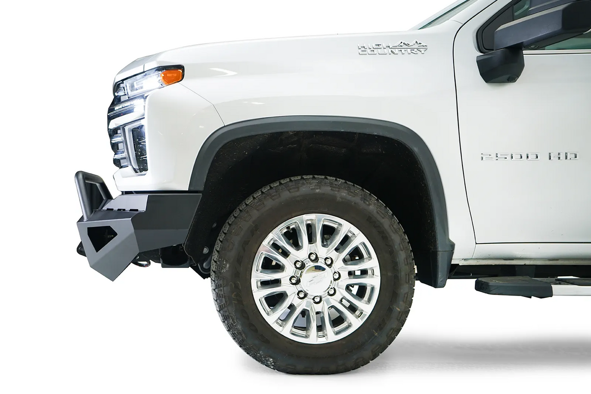 Fab Fours Red Steel front bumper with pre-runner guard on a white Chevrolet Silverado 2500HD, close-up front corner view from the driver side, showing the angular bumper end and pre-runner guard upright