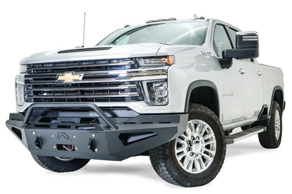 Fab Fours Red Steel front bumper with pre-runner guard on a white Chevrolet Silverado 2500HD, front driver-side three-quarter view, showing the pre-runner guard, angular bumper face, Fab Fours logo and winch hook