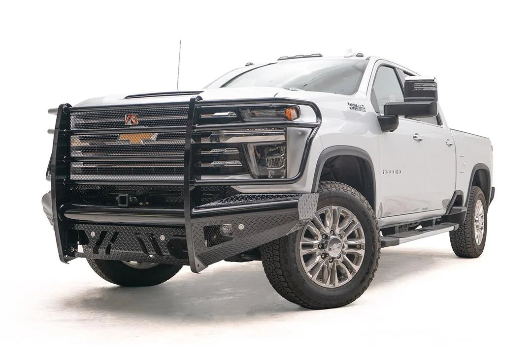 Fab Fours Black Steel front bumper with full guard on a white Chevrolet Silverado 2500HD, front driver-side three-quarter view, showing the full grille guard hoops, diamond-plate end caps and lower skid openings