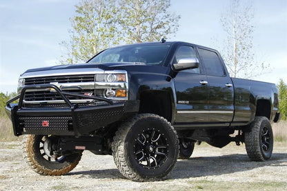 Fab Fours Black Steel front bumper with pre-runner guard on a black lifted Chevrolet Silverado 2500HD, outdoor front driver-side three-quarter view, showing the tubular pre-runner hoop, diamond-plate face and red logo plate