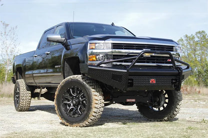 Fab Fours Black Steel front bumper with pre-runner guard on a black lifted Chevrolet Silverado 2500HD, outdoor front passenger-side three-quarter view, showing the tubular pre-runner hoop, diamond-plate face and red logo plate