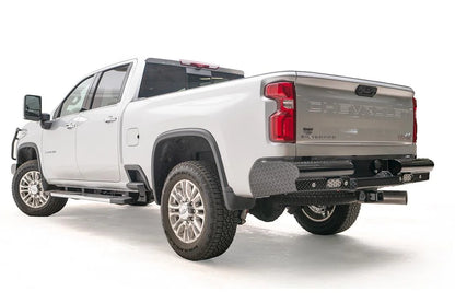 Fab Fours Black Steel rear bumper on a white Chevrolet Silverado 2500HD, rear driver-side three-quarter view, showing the diamond-plate end cap, integrated rear lights and wraparound corner