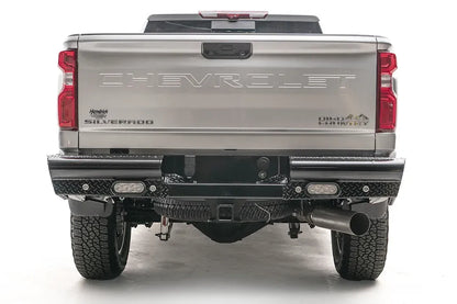 Fab Fours Black Steel rear bumper on a white Chevrolet Silverado 2500HD, straight-on rear view, showing the full-width diamond-plate bumper, recessed lights and center hitch receiver