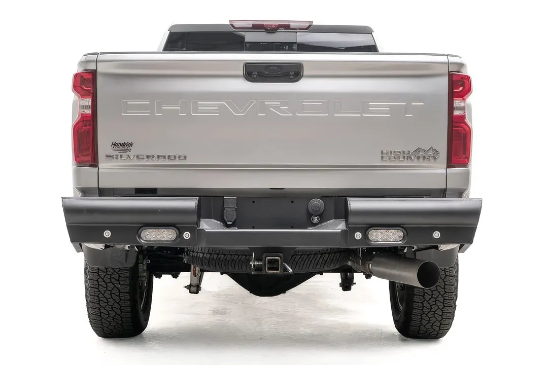 Fab Fours Black Steel Elite rear bumper on a white Chevrolet Silverado 2500HD, straight-on rear view, showing the full-width black steel bumper, recessed rear lights and center hitch receiver