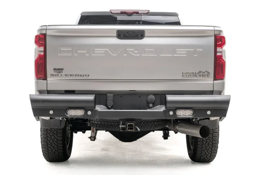 Fab Fours Black Steel Elite rear bumper on a white Chevrolet Silverado 2500HD, straight-on rear view, showing the full-width black steel bumper, recessed rear lights and center hitch receiver
