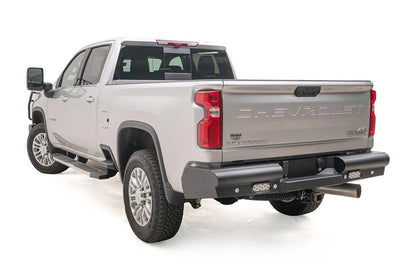 Fab Fours Black Steel Elite rear bumper on a white Chevrolet Silverado 2500HD, rear driver-side three-quarter view, showing the angled end cap, flush-mount lights and center hitch area