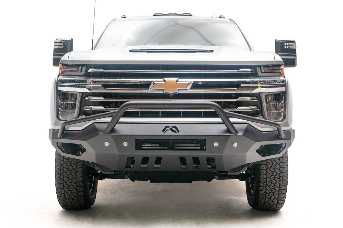 Fab Fours Vengeance front bumper with pre-runner guard on a white Chevrolet Silverado 2500HD, straight-on front view, showing the tubular pre-runner hoop, center light bar cutout and slotted skid plate