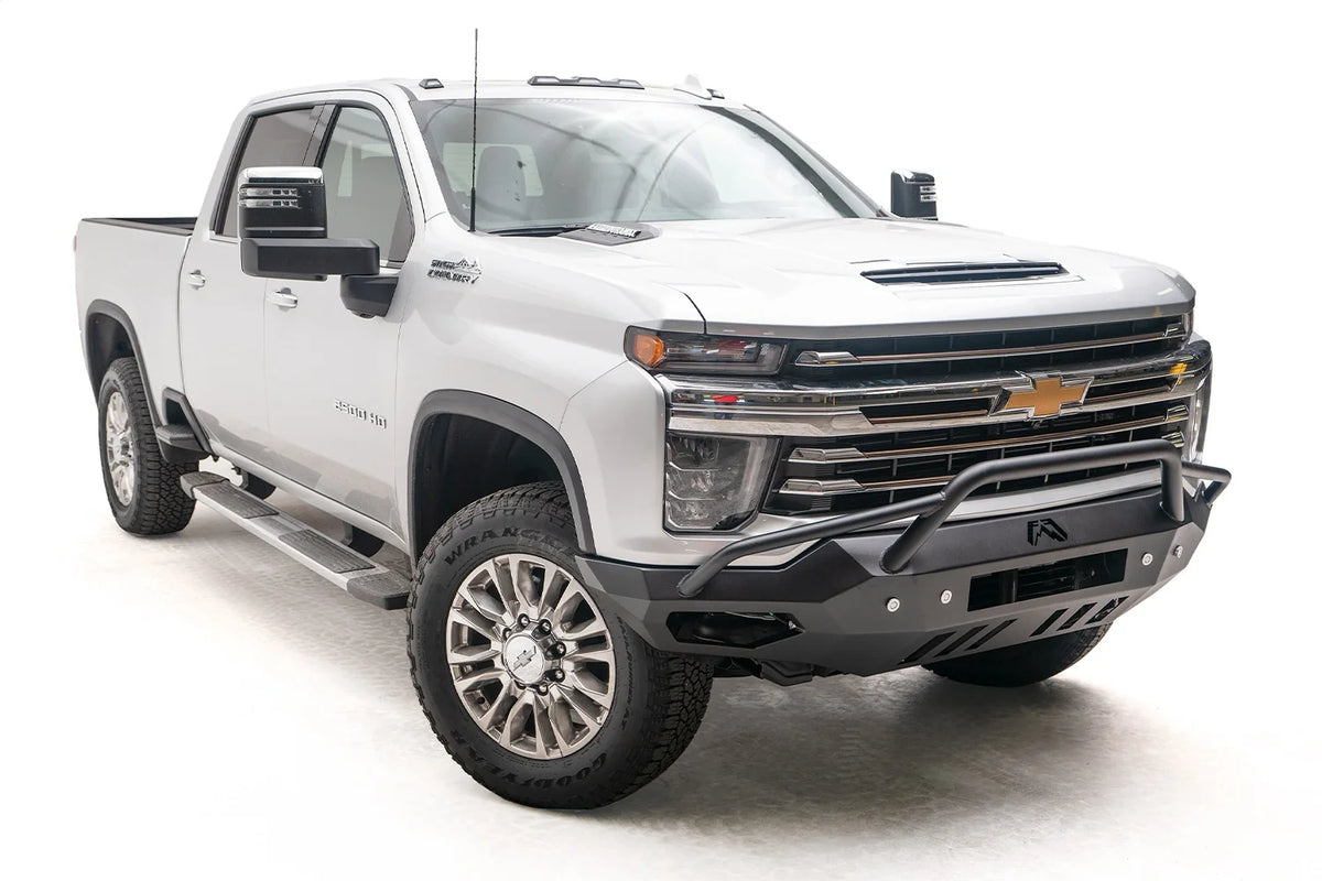 Fab Fours Vengeance front bumper with pre-runner guard on a white Chevrolet Silverado 2500HD, front passenger-side three-quarter view, showing the pre-runner hoop, angular bumper wing and lower skid plate
