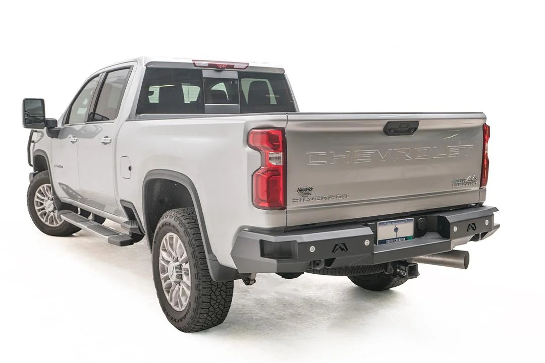 Fab Fours Premium rear bumper on a silver Chevrolet Silverado 2500HD, rear driver-side three-quarter view, showing the black steel bumper face, integrated rear lights and wraparound corner
