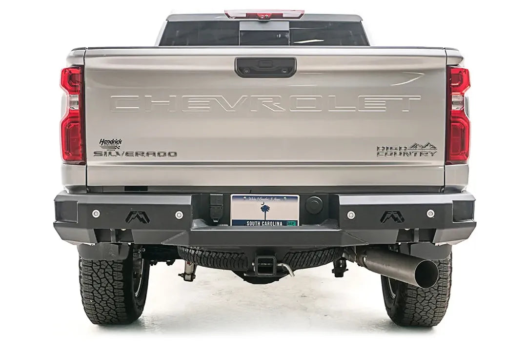 Fab Fours Premium rear bumper on a silver Chevrolet Silverado 2500HD, straight-on rear view, showing the full-width bumper, flush-mount lights, logo cutouts and center hitch receiver