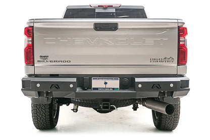 Fab Fours Premium rear bumper on a silver Chevrolet Silverado 2500HD, straight-on rear view, showing the full-width bumper, flush-mount lights, logo cutouts and center hitch receiver