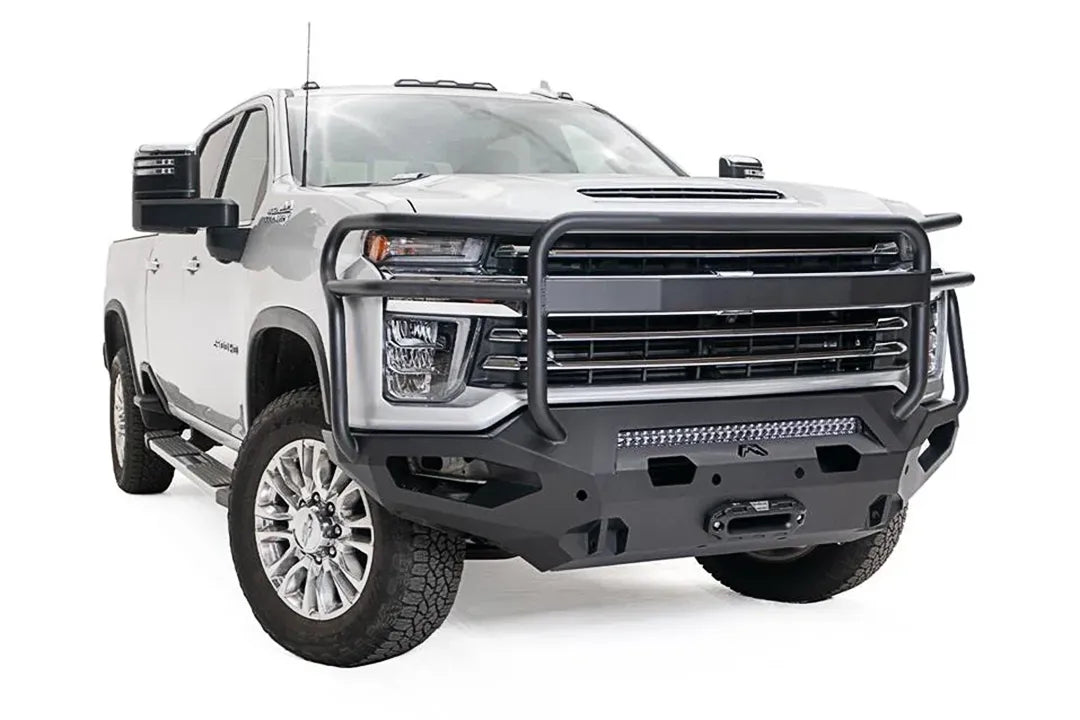 Fab Fours Matrix front bumper with full guard on a white Chevrolet Silverado 2500HD, front driver-side three-quarter view, showing the tubular full grille guard, integrated light bar and recessed winch mount