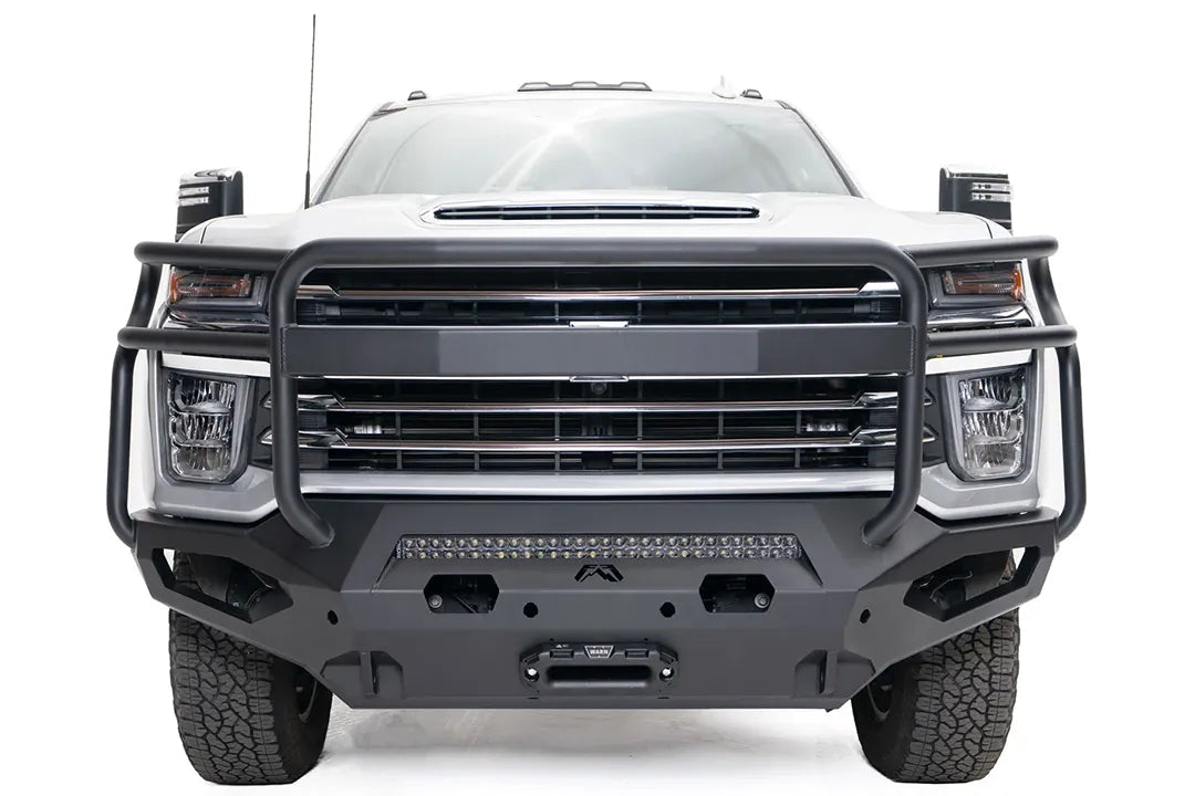 Fab Fours Matrix front bumper with full guard on a white Chevrolet Silverado 2500HD, straight-on front view, showing the full-width tubular guard, center light bar and winch fairlead opening