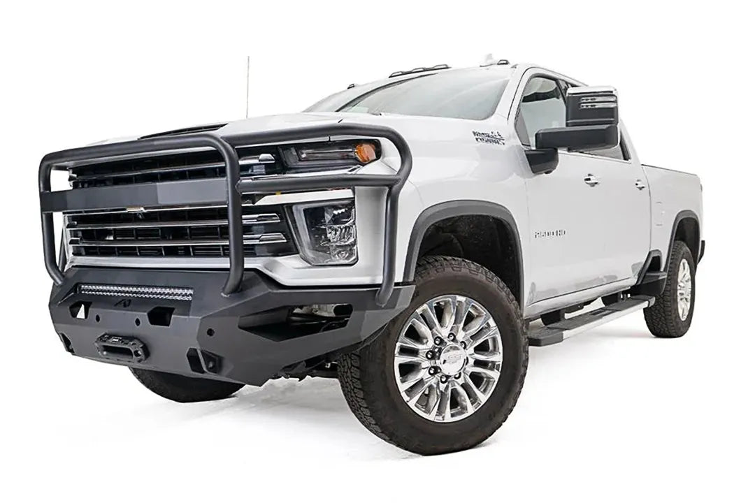 Fab Fours Matrix front bumper with full guard on a white Chevrolet Silverado 2500HD, front passenger-side three-quarter view, showing the tubular grille guard, integrated light bar and winch mount