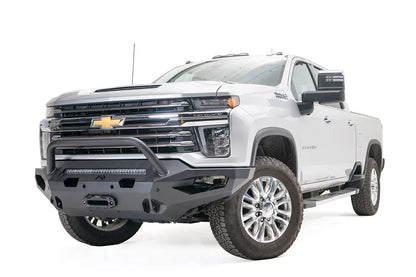 Fab Fours Matrix front bumper with pre-runner guard on a white Chevrolet Silverado 2500HD, front driver-side three-quarter view, showing the pre-runner hoop, center light bar and winch fairlead opening