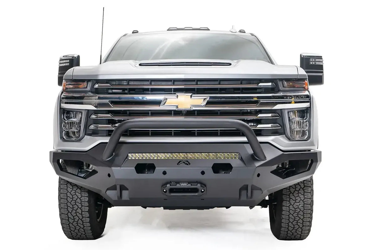 Fab Fours Matrix front bumper with pre-runner guard on a white Chevrolet Silverado 2500HD, straight-on front view, showing the tubular pre-runner hoop, center light bar and winch mount