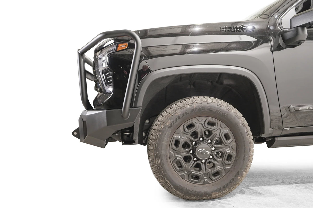 Fab Fours Premium Winch front bumper with full guard on a dark gray Chevrolet Silverado 2500HD, side close-up of the front corner, showing the guard upright, bumper end wing and shackle mount