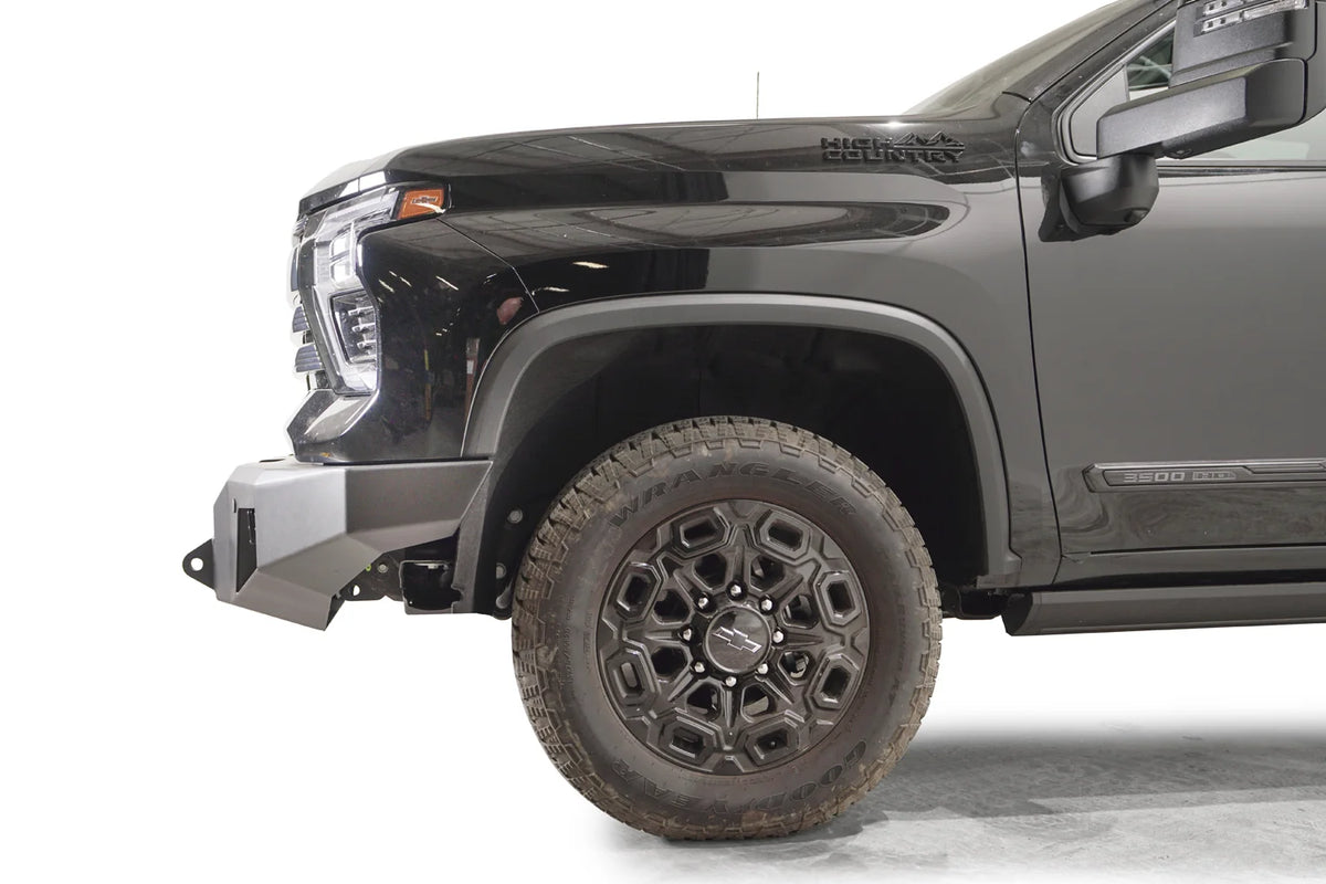Fab Fours Premium Winch front bumper on a dark gray Chevrolet Silverado 2500HD, side close-up of the front corner, showing the bumper end wing, shackle mount and wheel clearance
