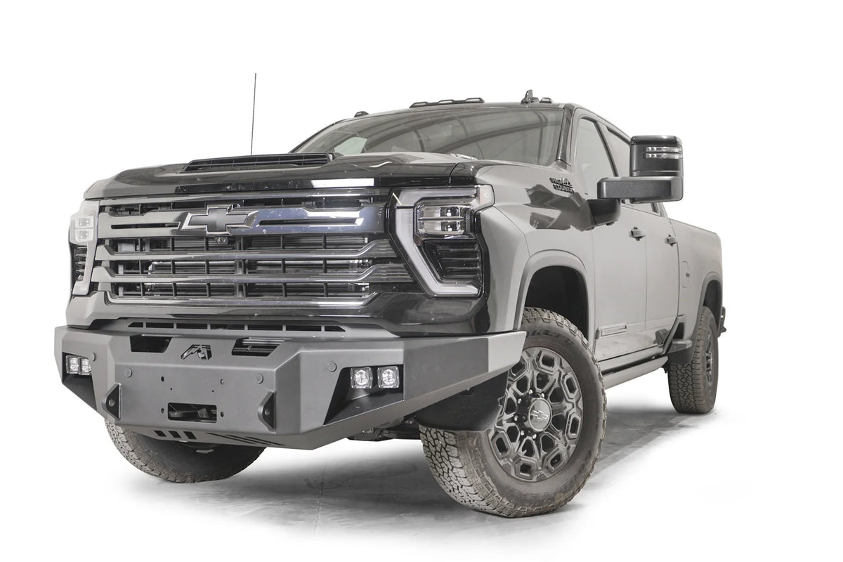 Fab Fours Premium Winch front bumper on a dark gray Chevrolet Silverado 2500HD, front driver-side three-quarter view, showing the no-guard design, winch mount and angled end wings