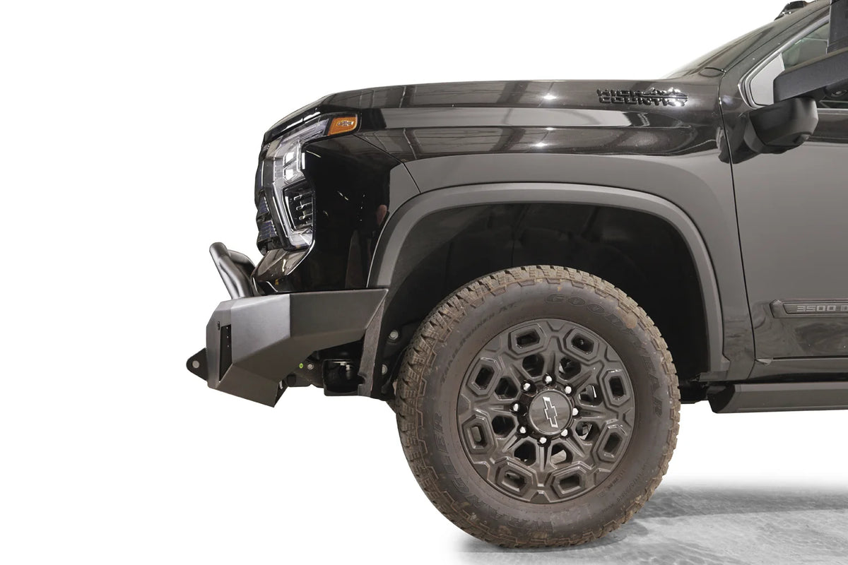 Fab Fours Premium Winch front bumper with pre-runner guard on a black Chevrolet Silverado 2500HD, side close-up of the front corner, showing the bumper end wing, shackle mount and pre-runner tube