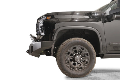 Fab Fours Premium Winch front bumper with pre-runner guard on a black Chevrolet Silverado 2500HD, side close-up of the front corner, showing the bumper end wing, shackle mount and pre-runner tube