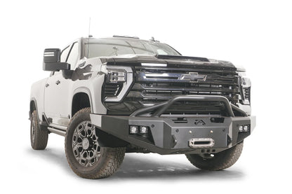 Fab Fours Premium Winch front bumper with pre-runner guard on a black Chevrolet Silverado 2500HD, front driver-side three-quarter view, showing the tubular pre-runner hoop, winch fairlead and pod light cutouts