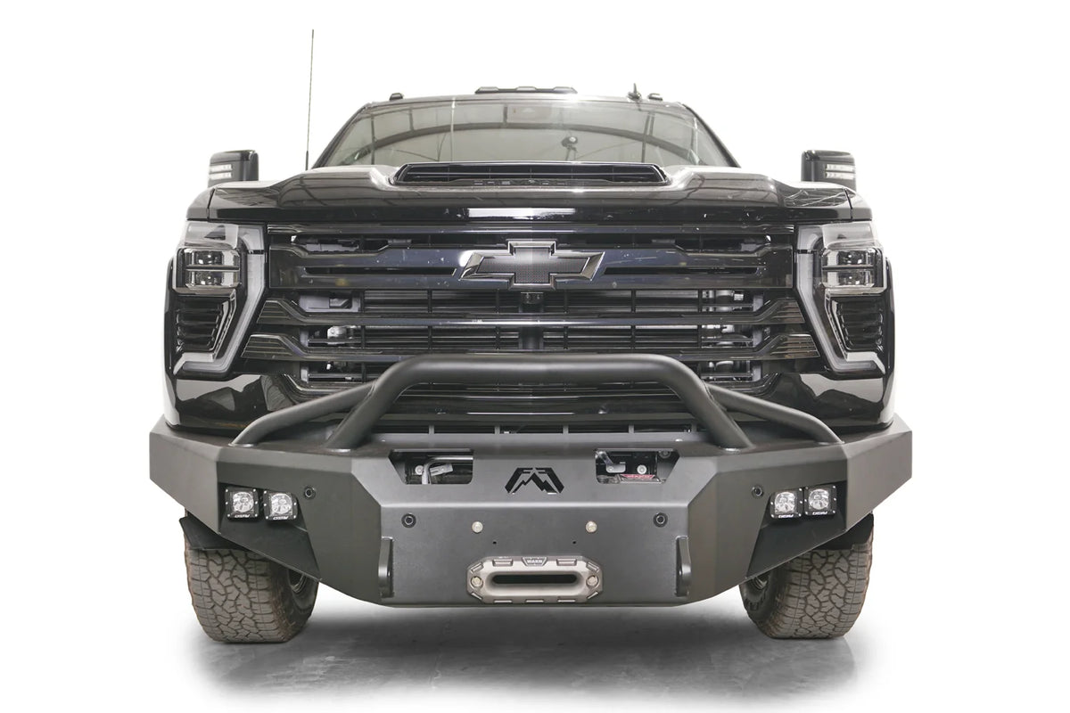 Fab Fours Premium Winch front bumper with pre-runner guard on a black Chevrolet Silverado 2500HD, straight-on front view, showing the pre-runner hoop, center winch fairlead and pod light cutouts