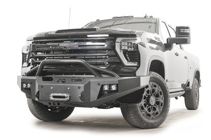 Fab Fours Premium Winch front bumper with pre-runner guard on a black Chevrolet Silverado 2500HD, front passenger-side three-quarter view, showing the tubular pre-runner hoop, winch fairlead and pod light cutouts