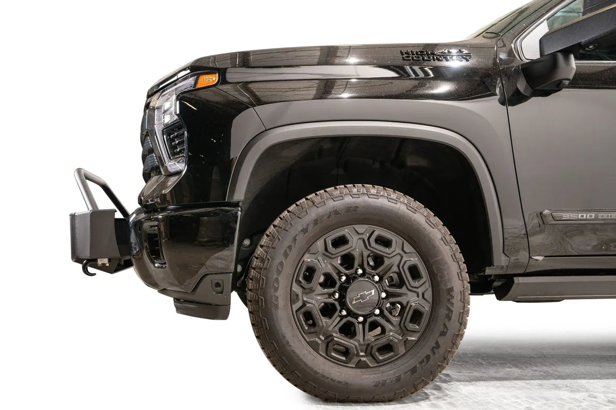 Fab Fours Winch Mount with pre-runner guard on a black Chevrolet Silverado 2500HD, side close-up of the front end, showing the mount's profile, pre-runner tube and factory bumper integration