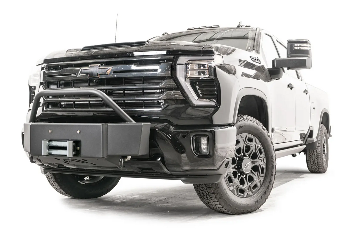 Fab Fours Winch Mount with pre-runner guard on a black Chevrolet Silverado 2500HD, front passenger-side three-quarter view, showing the tubular pre-runner hoop, boxed winch plate and roller fairlead