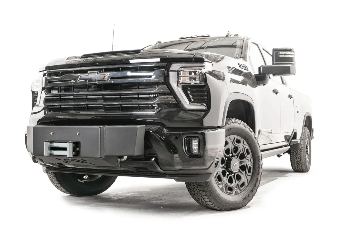 Fab Fours Winch Mount on a black Chevrolet Silverado 2500HD, front passenger-side three-quarter view, showing the no-guard winch mount, roller fairlead and factory fog light surround