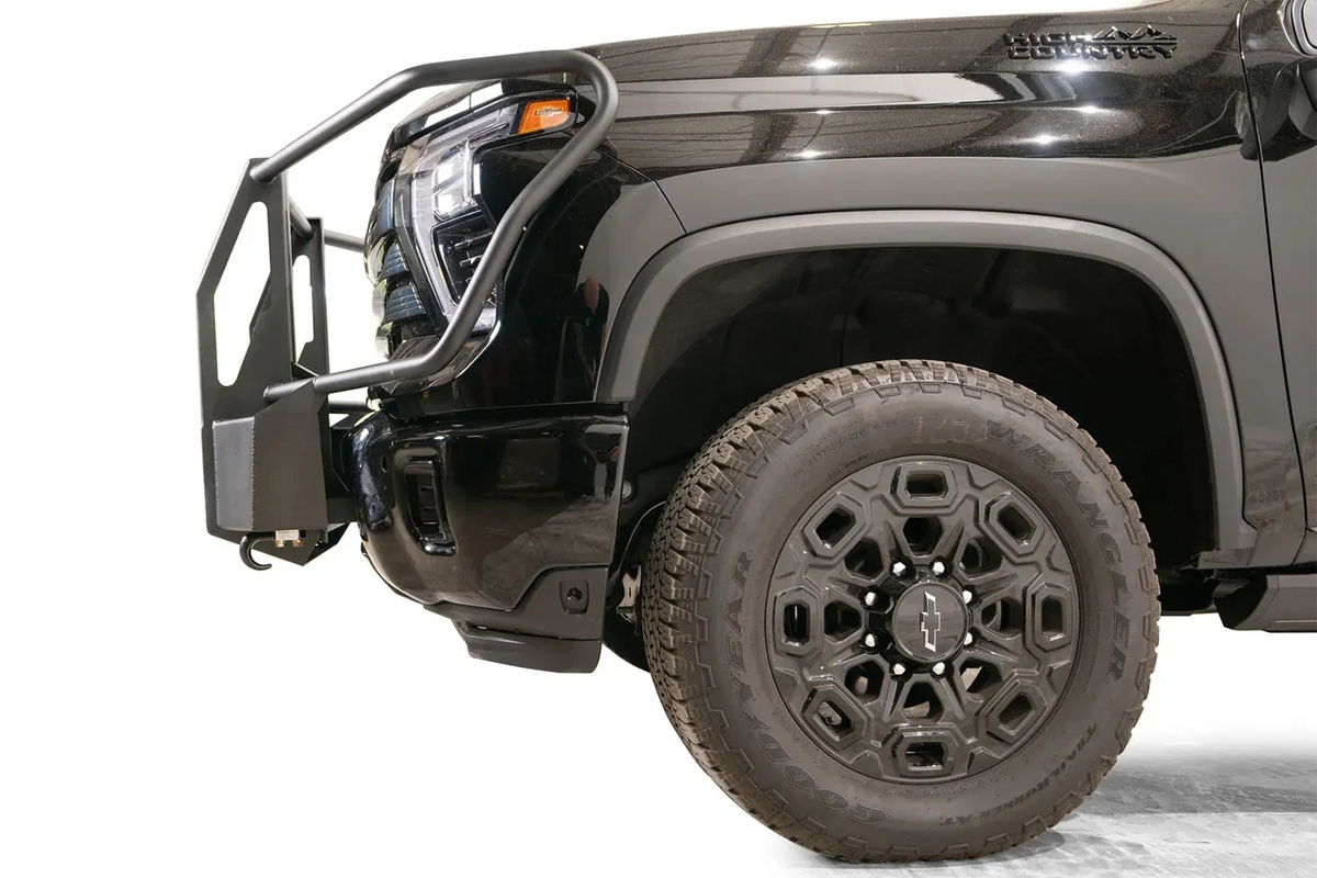 Fab Fours Winch Mount with full guard on a black Chevrolet Silverado 2500HD, side close-up of the front end, showing the guard hoop profile, mount depth and factory bumper fit