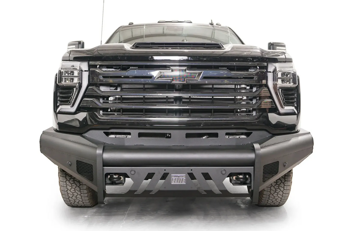 Fab Fours Black Steel Elite front bumper on a black Chevrolet Silverado 2500HD, straight-on front view, showing the full-width bumper, slotted center skid plate and pod light openings
