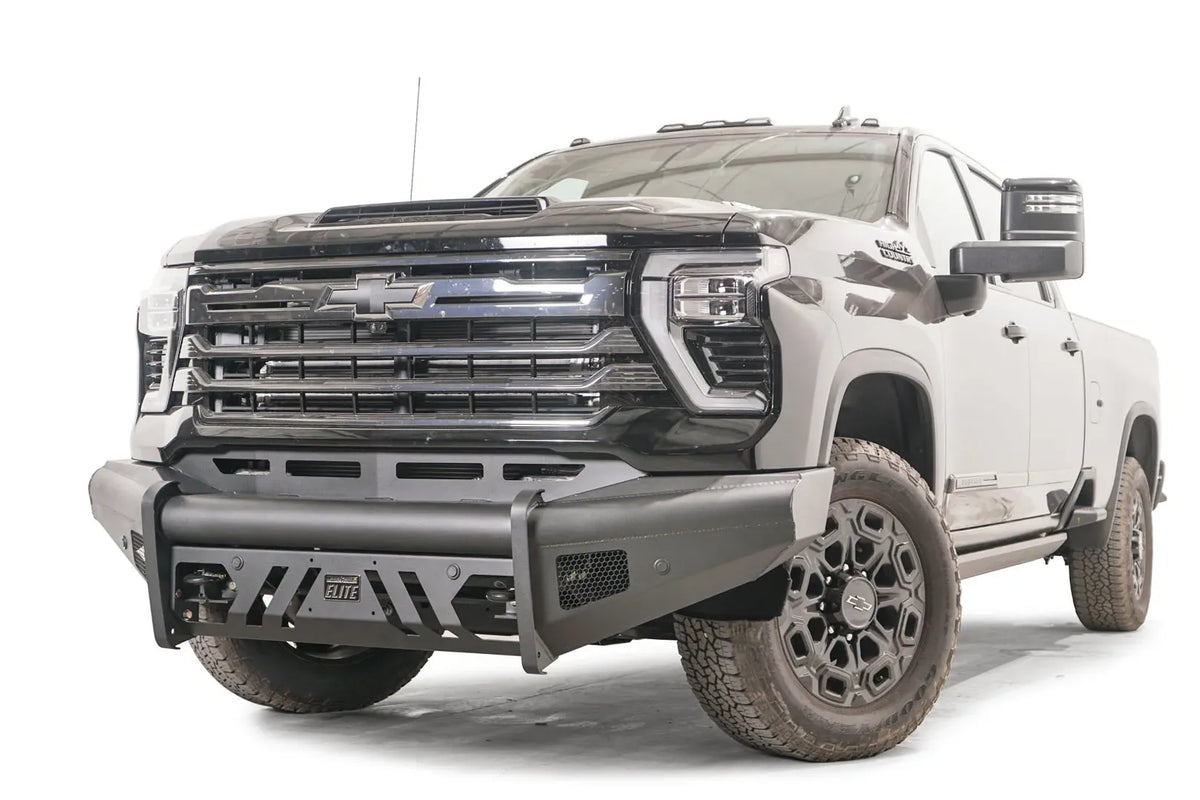 Fab Fours Black Steel Elite front bumper on a black Chevrolet Silverado 2500HD, front driver-side three-quarter view, showing the no-guard design, slotted skid plate and mesh side vents