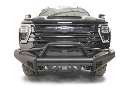 Fab Fours Black Steel Elite front bumper with pre-runner guard on a black Chevrolet Silverado 2500HD, straight-on front view, showing the tubular pre-runner hoop, slotted center skid plate and pod light openings
