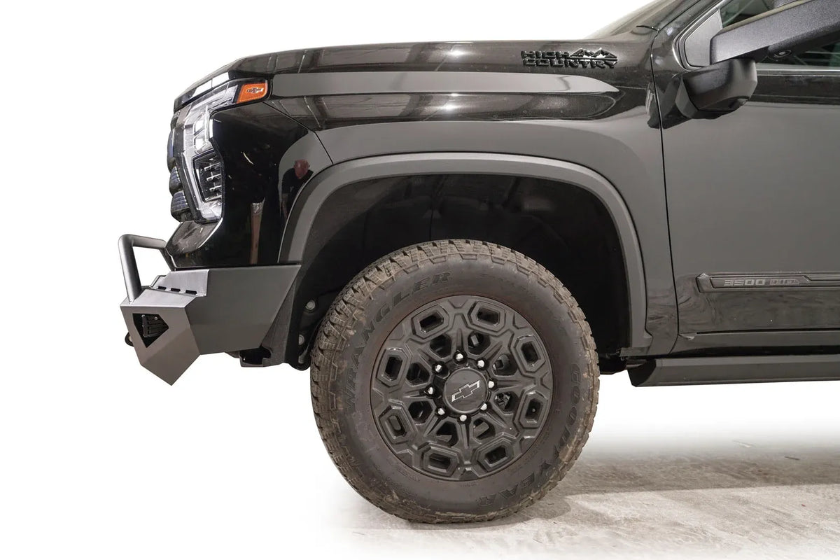 Fab Fours Red Steel front bumper with pre-runner guard on a black Chevrolet Silverado 2500HD, side close-up of the front corner, showing the pre-runner tube, shackle mount and bumper end wing