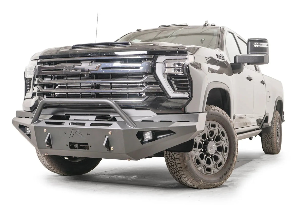 Fab Fours Red Steel front bumper with pre-runner guard on a black Chevrolet Silverado 2500HD, front driver-side three-quarter view, showing the tubular pre-runner hoop, winch mount plate and pod light openings