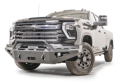 Fab Fours Red Steel front bumper with pre-runner guard on a black Chevrolet Silverado 2500HD, front driver-side three-quarter view, showing the tubular pre-runner hoop, winch mount plate and pod light openings