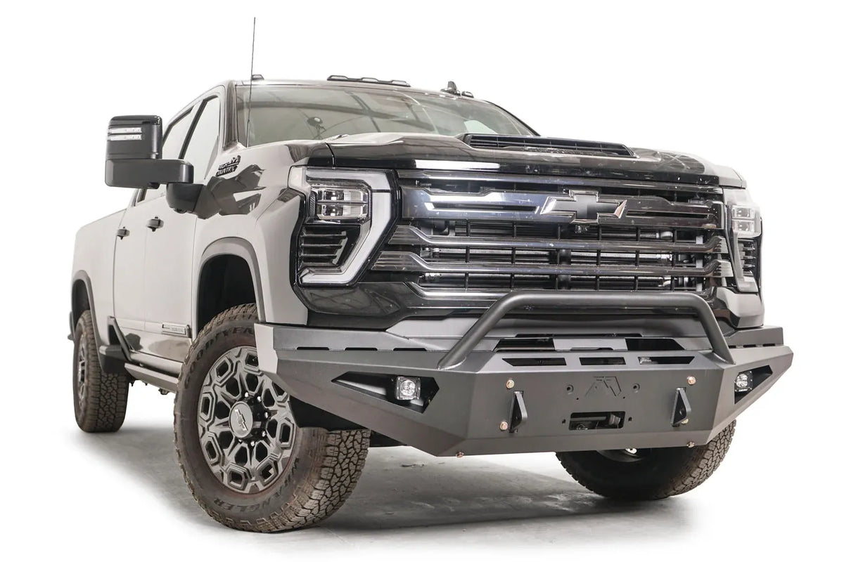 Fab Fours Red Steel front bumper with pre-runner guard on a black Chevrolet Silverado 2500HD, front passenger-side three-quarter view, showing the pre-runner hoop, angled end wing and pod light opening