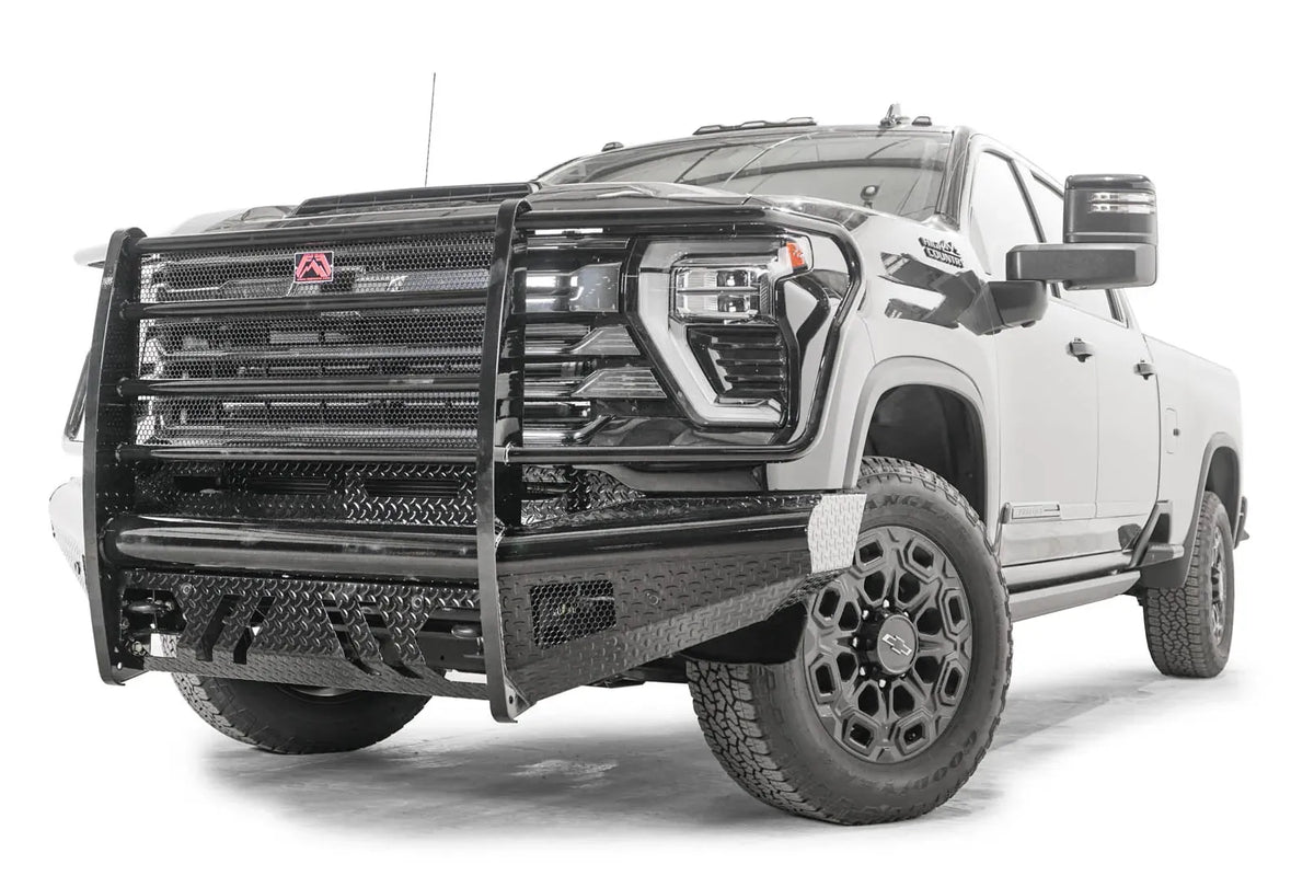 Fab Fours Black Steel front bumper with full guard on a black Chevrolet Silverado 2500HD, front driver-side three-quarter view, showing the mesh-filled full grille guard, diamond-plate face and slotted skid plate