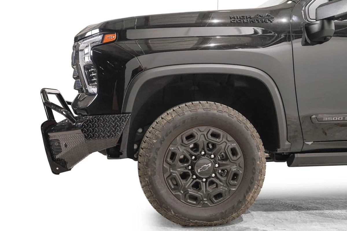 Fab Fours Black Steel front bumper with pre-runner guard on a black Chevrolet Silverado 2500HD, side close-up of the front corner, showing the pre-runner tube, diamond-plate end wing and wheel clearance
