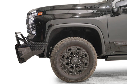 Fab Fours Black Steel front bumper with pre-runner guard on a black Chevrolet Silverado 2500HD, side close-up of the front corner, showing the pre-runner tube, diamond-plate end wing and wheel clearance