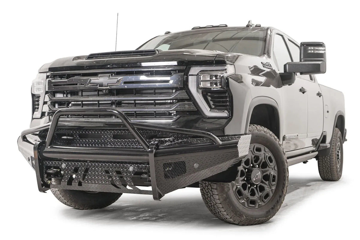 Fab Fours Black Steel front bumper with pre-runner guard on a black Chevrolet Silverado 2500HD, front driver-side three-quarter view, showing the tubular pre-runner hoop, diamond-plate face and slotted skid plate