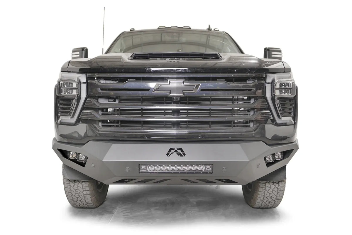 Fab Fours Vengeance front bumper on a dark gray Chevrolet Silverado 2500HD, straight-on front view, showing the no-guard design, integrated center light bar and pod light openings