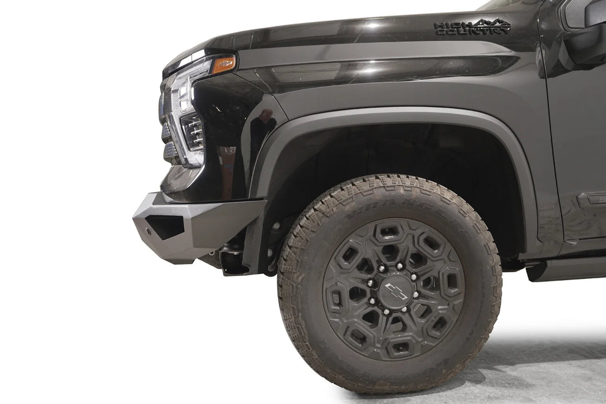 Fab Fours Vengeance front bumper on a black Chevrolet Silverado 2500HD, side close-up of the front corner, showing the angular bumper end wing and wheel clearance