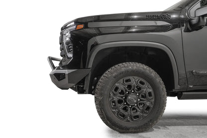 Fab Fours Vengeance front bumper with pre-runner guard on a black Chevrolet Silverado 2500HD, side close-up of the front corner, showing the pre-runner tube, angular end wing and wheel clearance