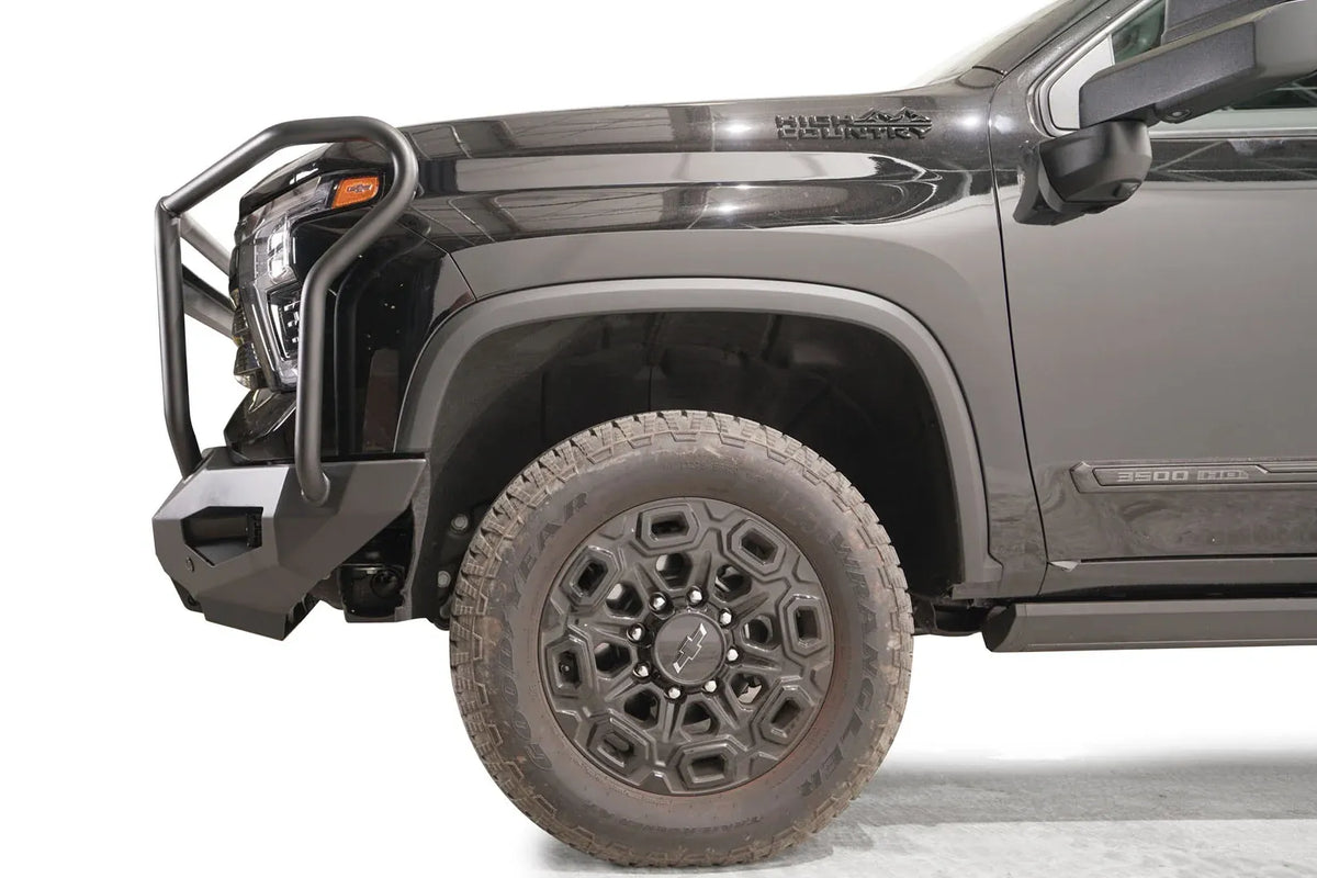 Fab Fours Matrix front bumper with full guard on a black Chevrolet Silverado 2500HD, side close-up of the front corner, showing the guard hoop profile, bumper end wing and wheel clearance