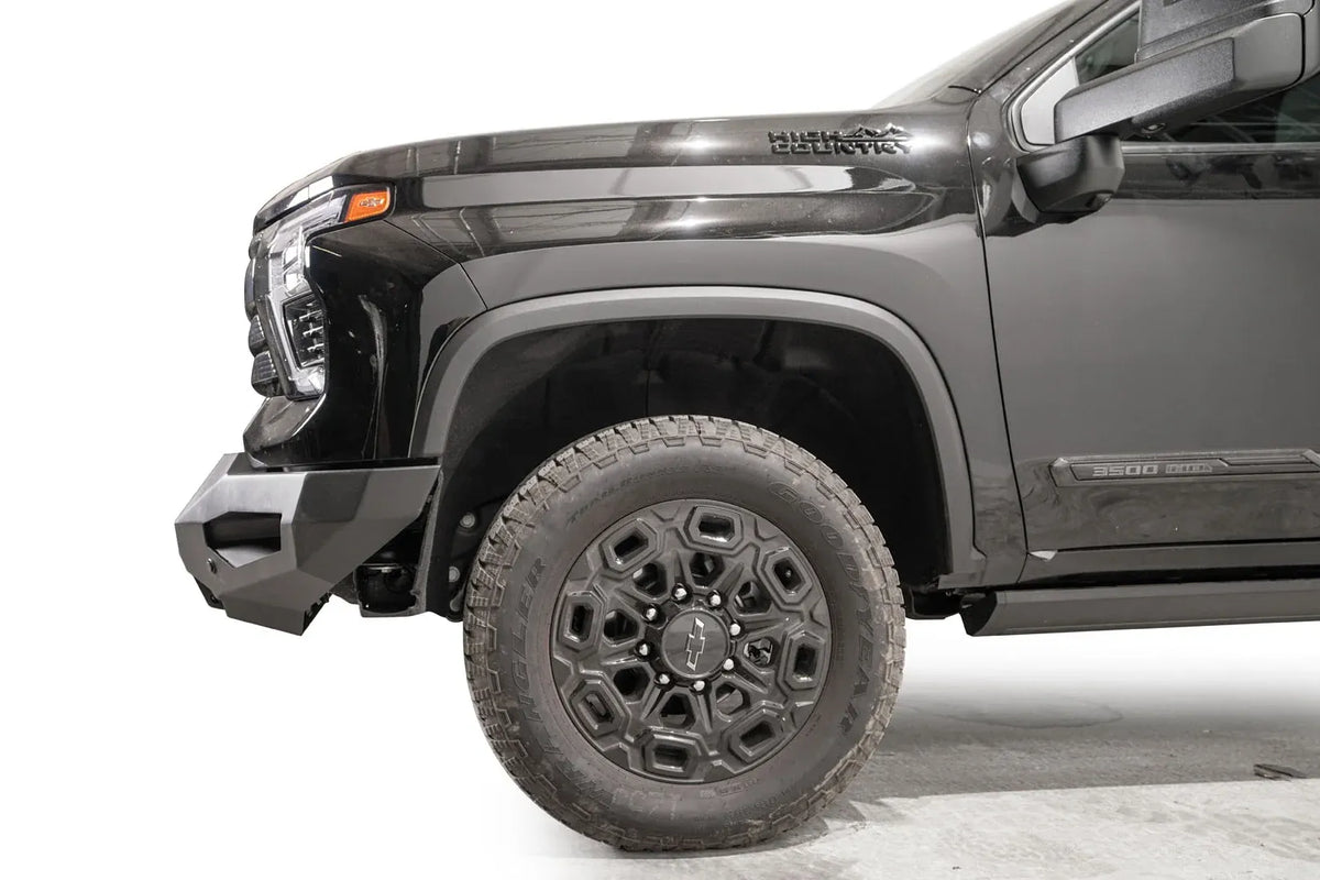 Fab Fours Matrix front bumper on a black Chevrolet Silverado 2500HD, side close-up of the front corner, showing the bumper end wing profile and wheel clearance