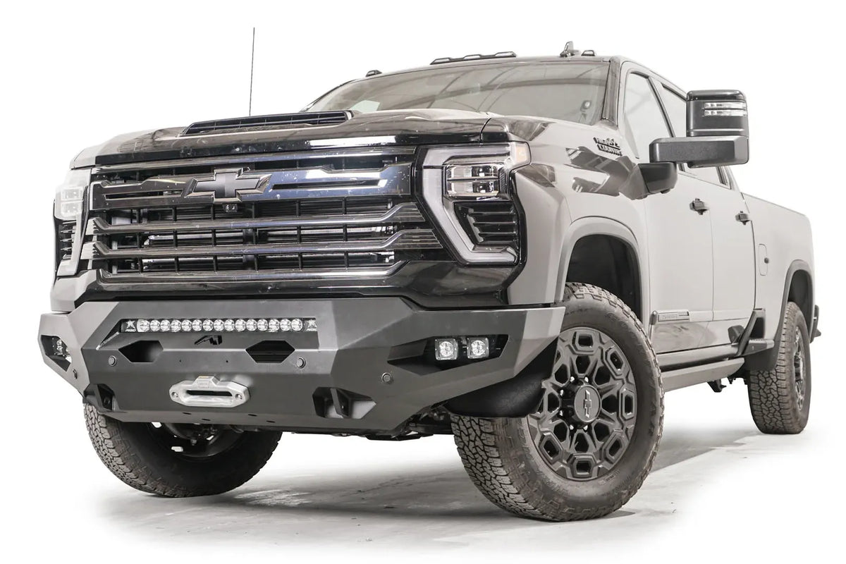 Fab Fours Matrix front bumper on a black Chevrolet Silverado 2500HD, front driver-side three-quarter view, showing the no-guard design, integrated light bar and winch fairlead